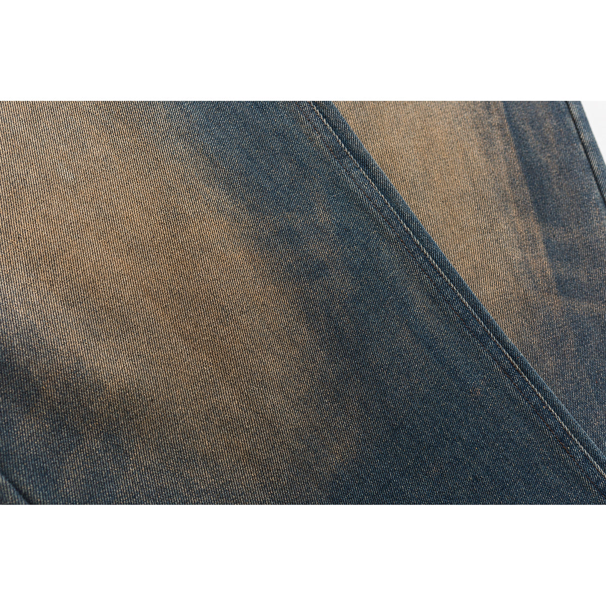 Extreme close-up of blue denim with a diagonal stitched seam and contrasting faded areas.