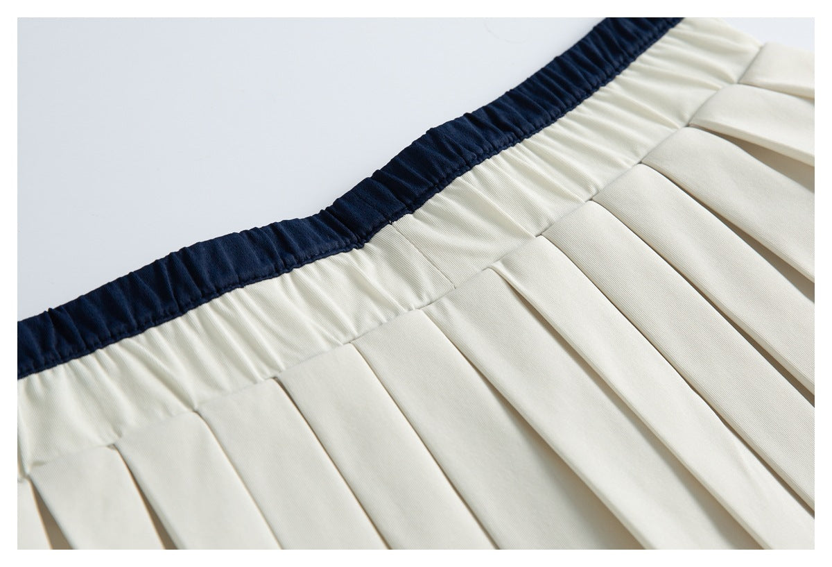 Close-up of an ivory pleated garment with a dark navy elastic waistband.