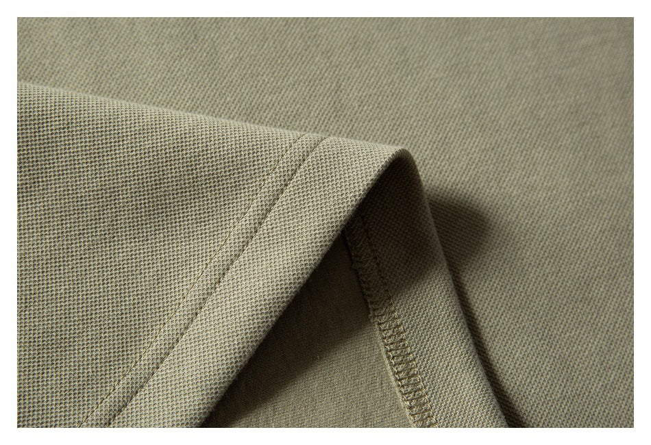 Close-up showing the textured fabric and overlocked seam of a muted olive-beige garment.