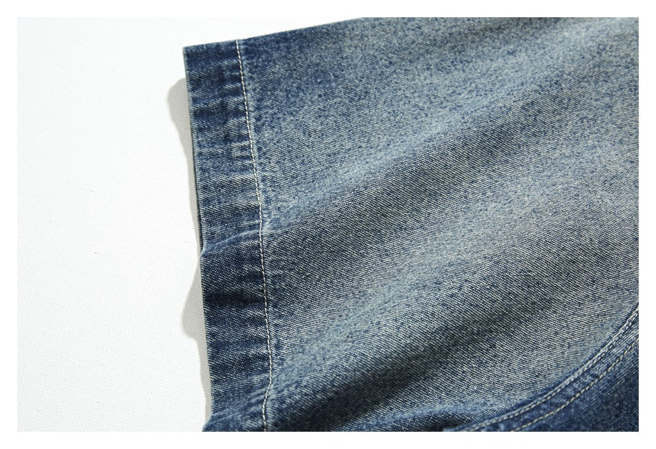 Close-up of a washed blue denim shirt edge and stitched seam.