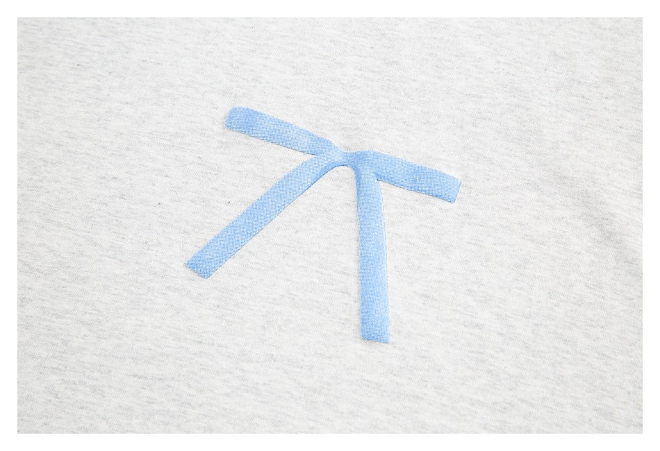Close-up of a blue bow motif on light gray fabric.