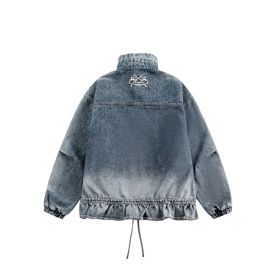 Back view of a washed blue denim jacket with a small embroidered upper-back motif, gathered cuffs and a ruffled hem.