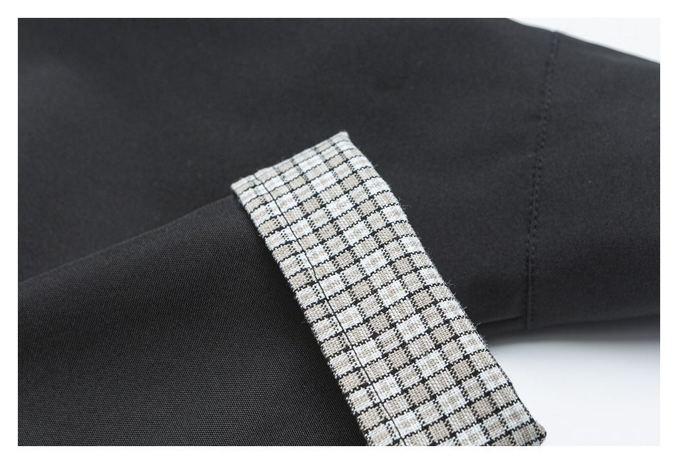 Close-up of black garment fabric with a black-and-white checked trim panel.