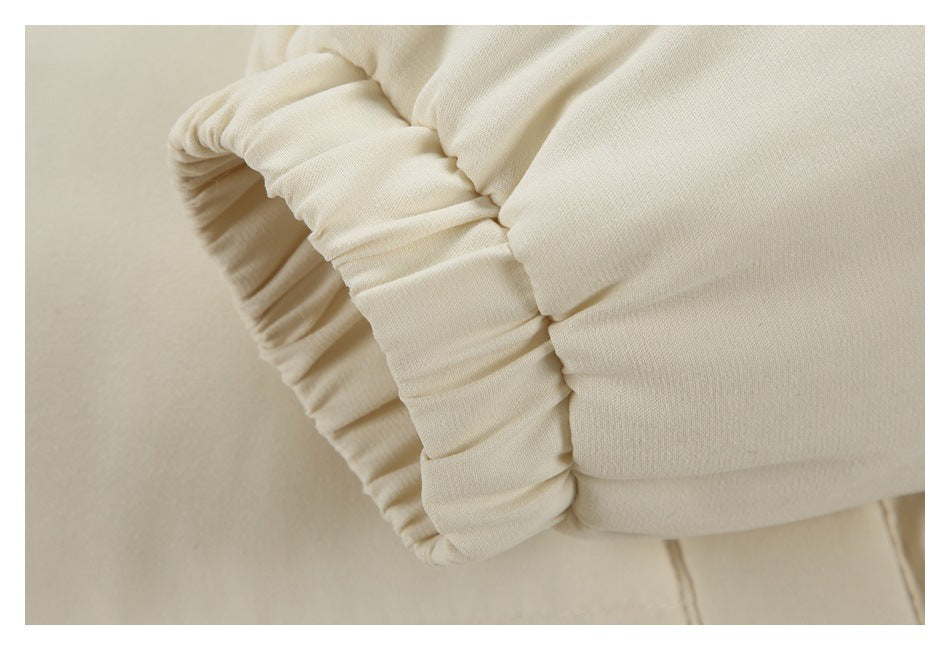 Close-up of a cream garment with a wide gathered, ruched edge.
