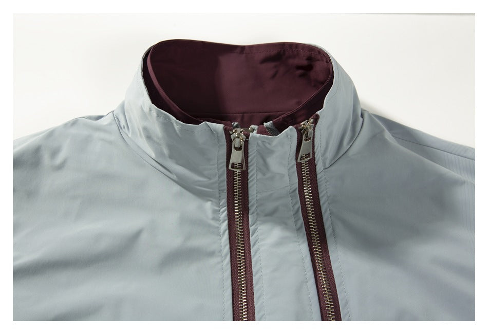 Close-up of the vest’s stand collar and two zippers, showing pale gray outer fabric and plum inner lining.
