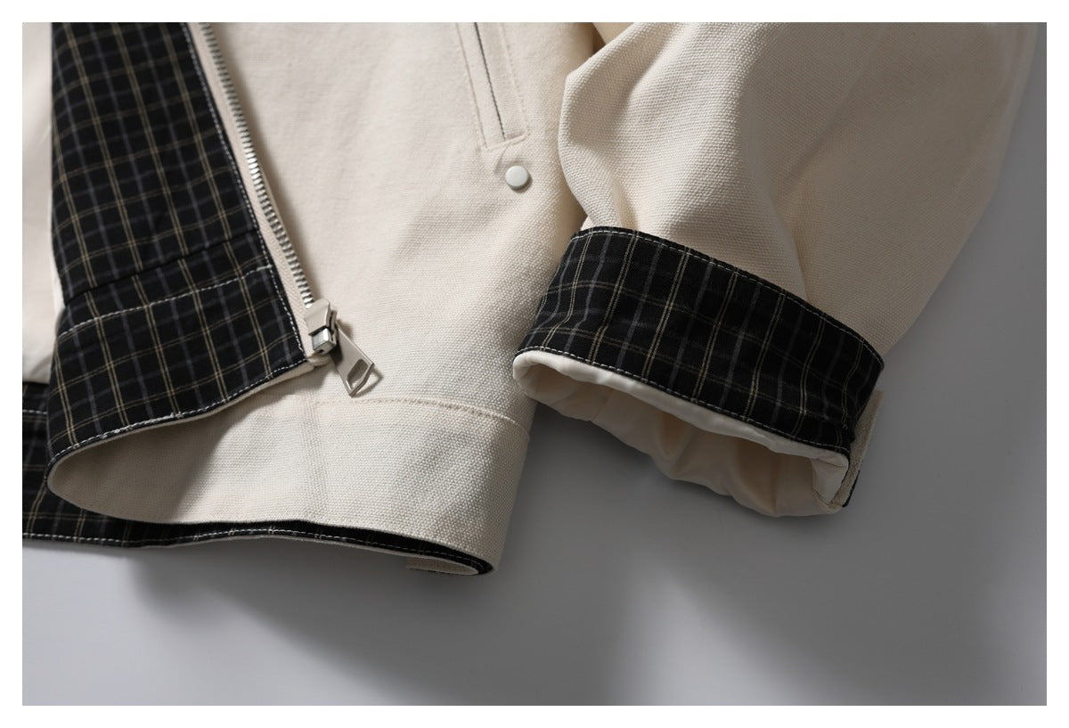 Close-up of the ivory jacket's front zipper, black plaid trim and matching plaid sleeve cuff.