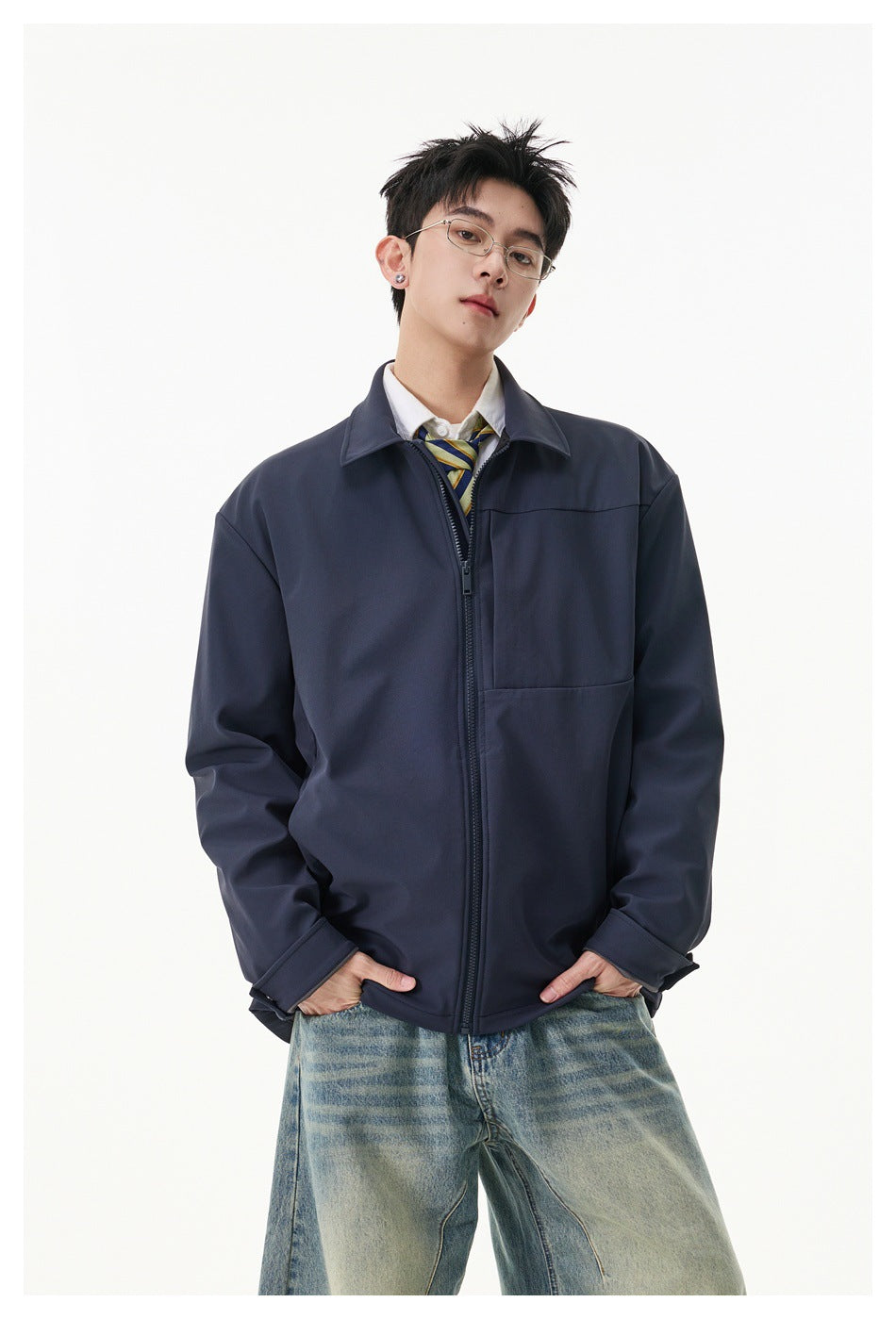 Model wearing a dark navy zip-front jacket with a pointed collar and chest panel, styled with a striped tie and jeans.