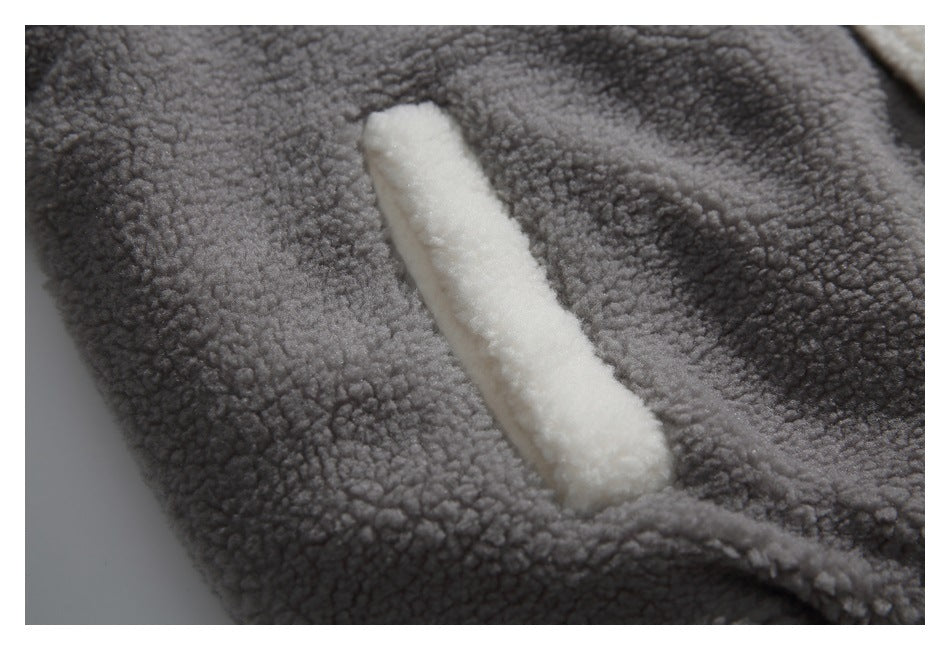 Close-up of a narrow cream-trimmed pocket opening on the gray textured jacket.