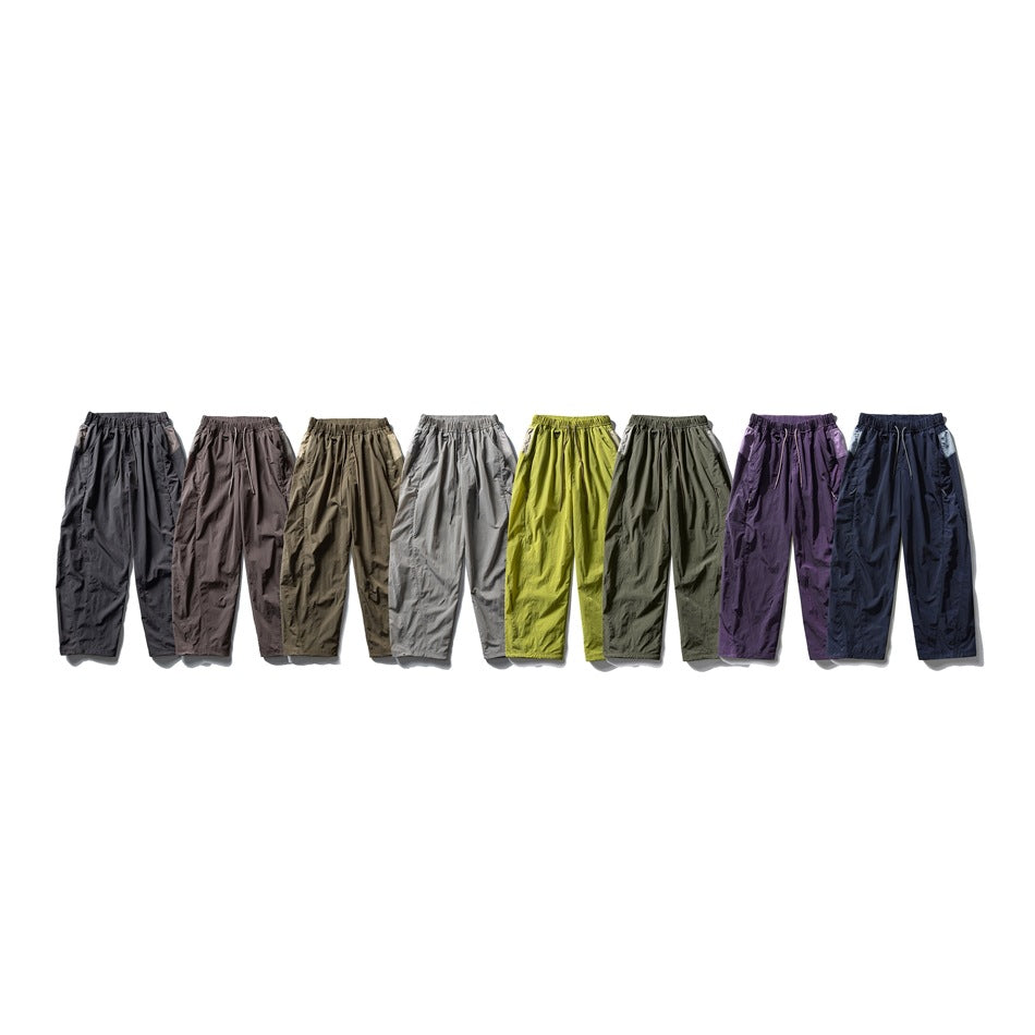 Eight pairs of loose drawstring pants shown together in charcoal, brown, olive, gray, lime, green, purple, and navy.
