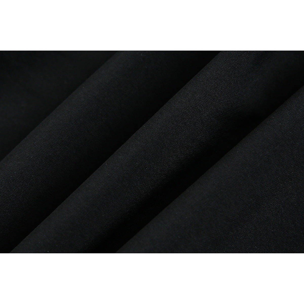 Extreme close-up of black fabric arranged in soft folds.