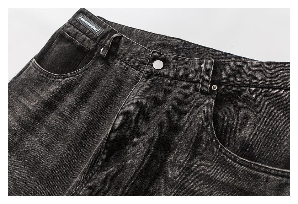 Close-up of the front waistband, metal button, belt loop and curved pockets on dark washed jeans.