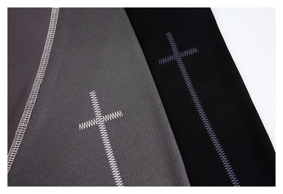 Close-up of gray and black fabric panels with contrasting overlock seams and cross-shaped zigzag stitching.