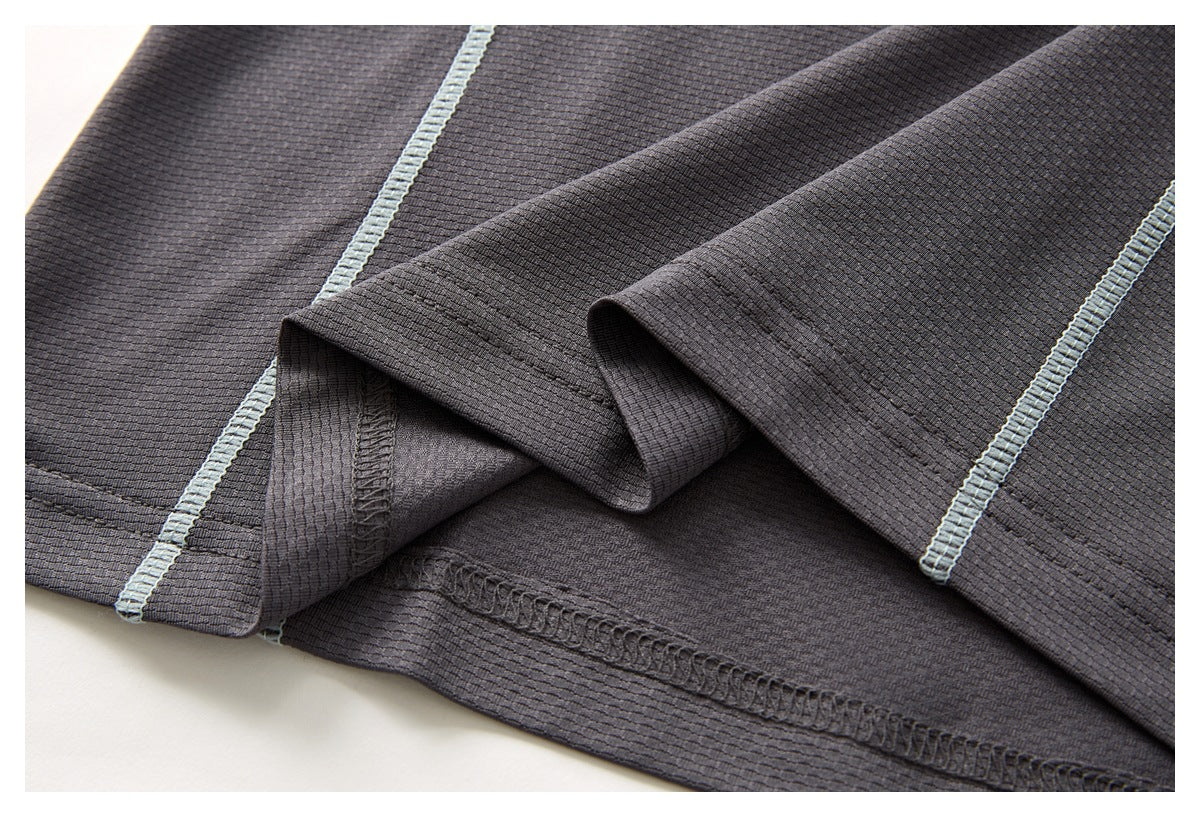Close-up of a dark charcoal garment hem with pale gray-blue overlock stitching and a folded edge.