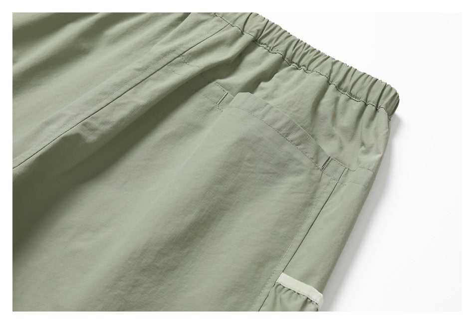 Close-up of the elastic waistband and large rear pocket on sage-green pants.