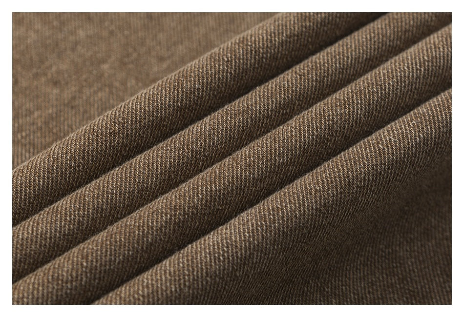 Close-up of brown twill fabric arranged in soft folds, showing its woven texture.