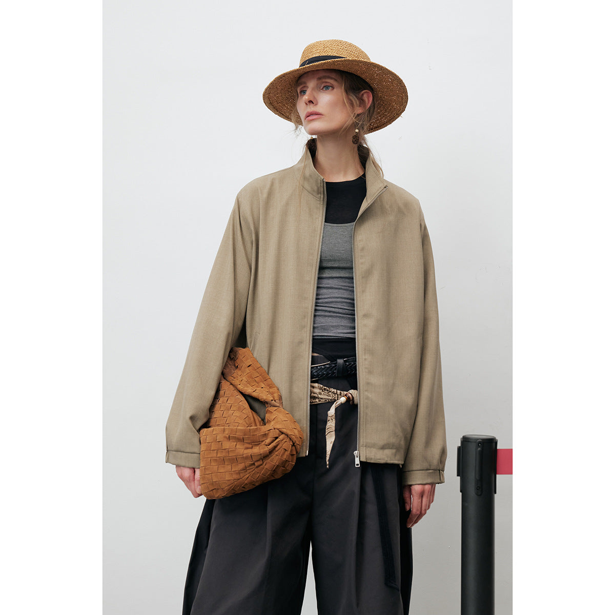 Model wearing an open taupe stand-collar jacket with a front zipper and layered tops, shown from the front.