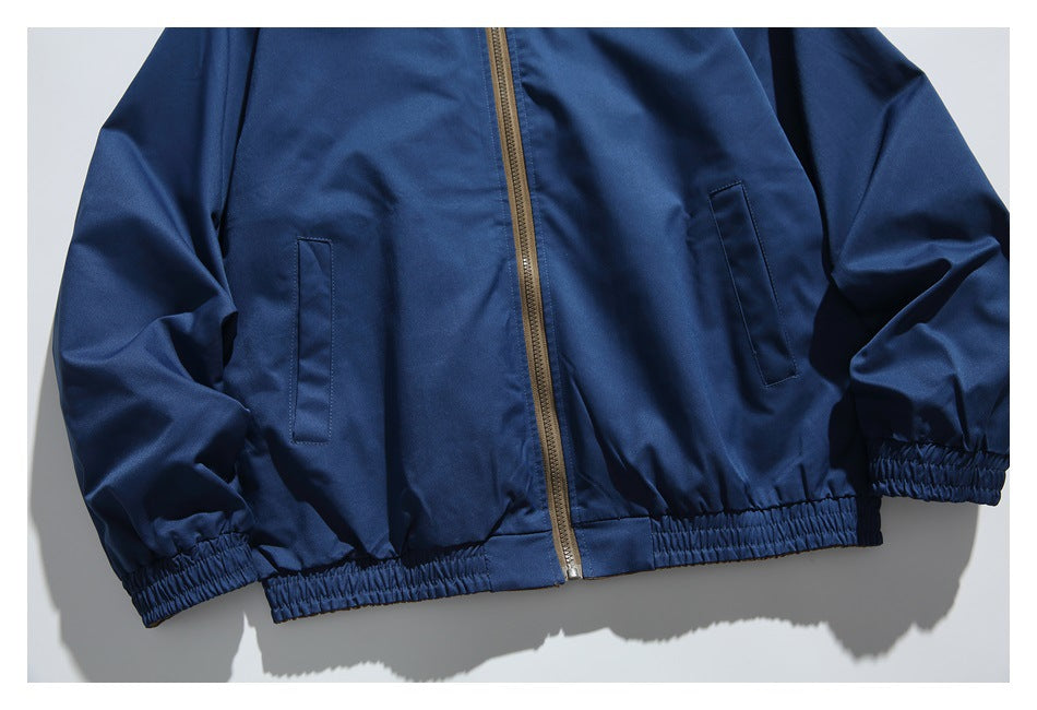 Close-up of the navy jacket's front pockets, tan zipper, elastic hem, and gathered cuffs.