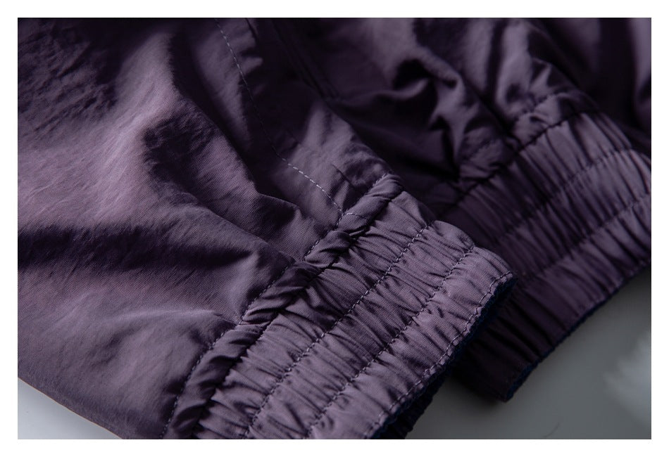 Close-up of a dark purple garment with a wide gathered elastic band and stitched seams.
