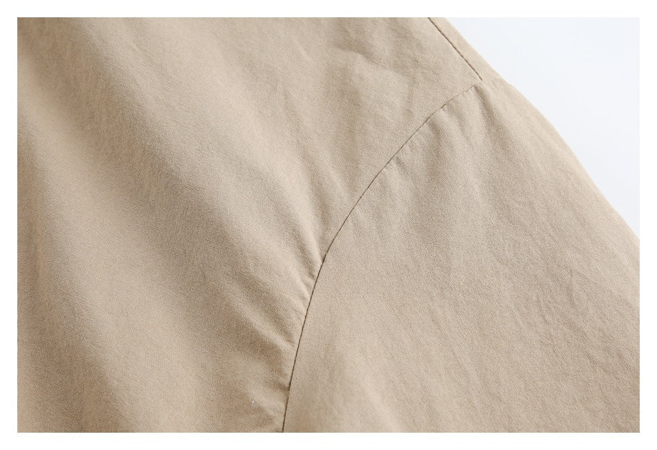 Close-up of the tan jacket's curved shoulder seam and smooth fabric surface.