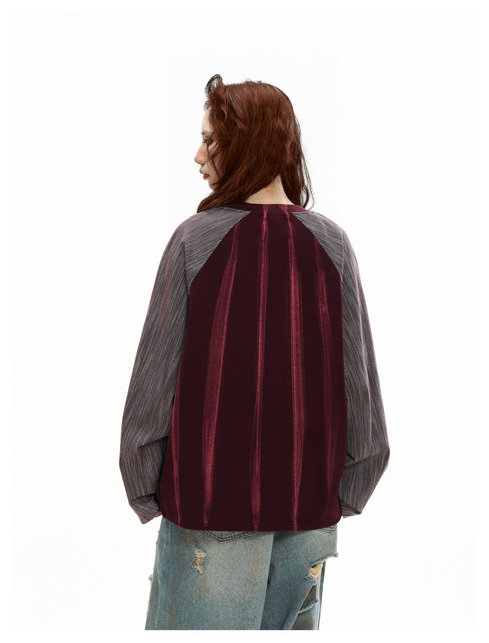 Back view of a model wearing a burgundy top with vertical stripes and gray pinstriped raglan sleeves.