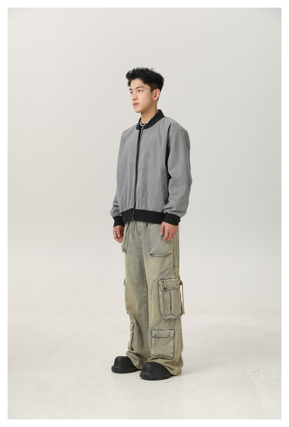 Model in a gray zip-front bomber jacket with black ribbed collar, cuffs and hem, shown at a three-quarter angle.