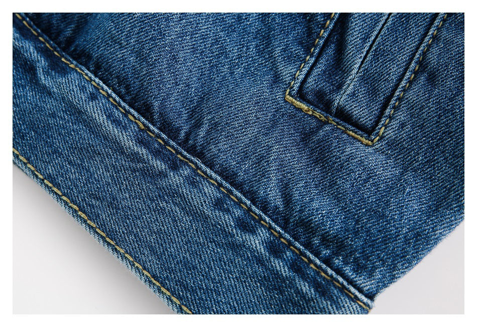 Close-up of a blue denim hem and pocket edge with contrasting topstitching.