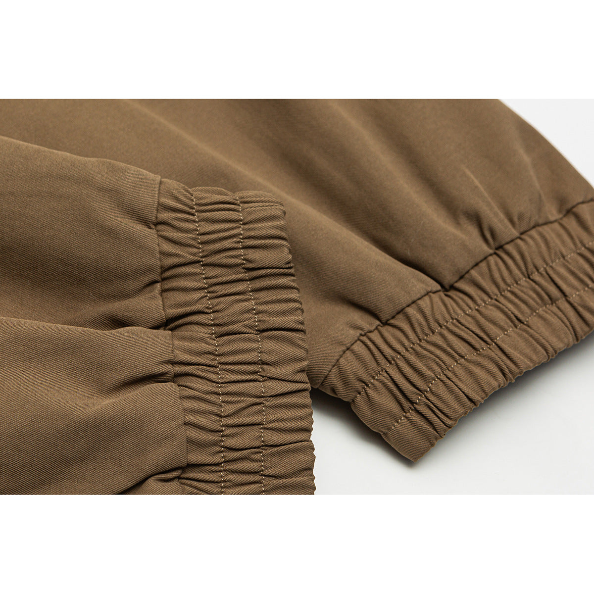 Close-up of a brown jacket’s gathered elastic cuff and waistband with stitched seams.