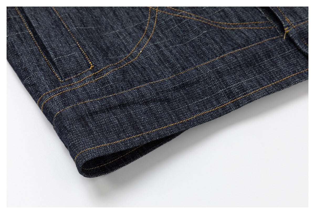 Close-up of the dark denim garment hem with parallel ochre stitching.