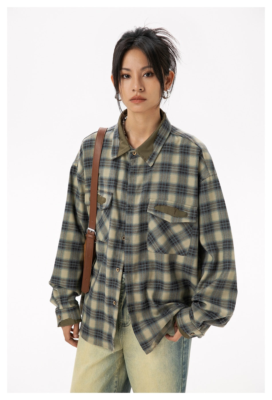 Model wearing an oversized plaid button-up shirt with pointed collar, contrasting olive panels and flap pockets.