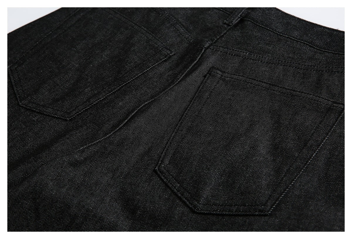 Close-up of the back of black denim trousers with two stitched patch pockets.