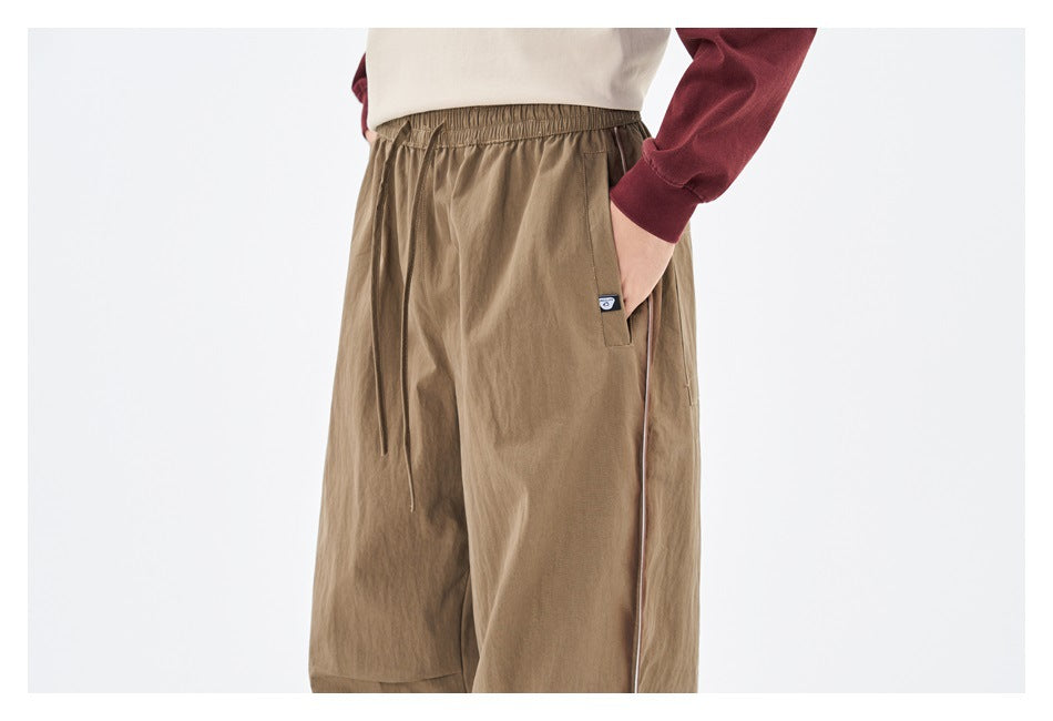 Close-up of khaki pants showing elastic drawstring waist, side pocket, small hip label and side piping on a model