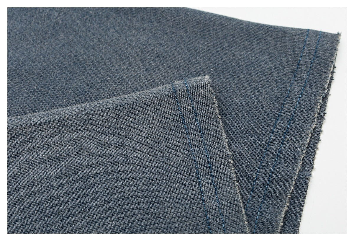 Close-up of blue-gray shirt fabric and overlapping stitched edges.