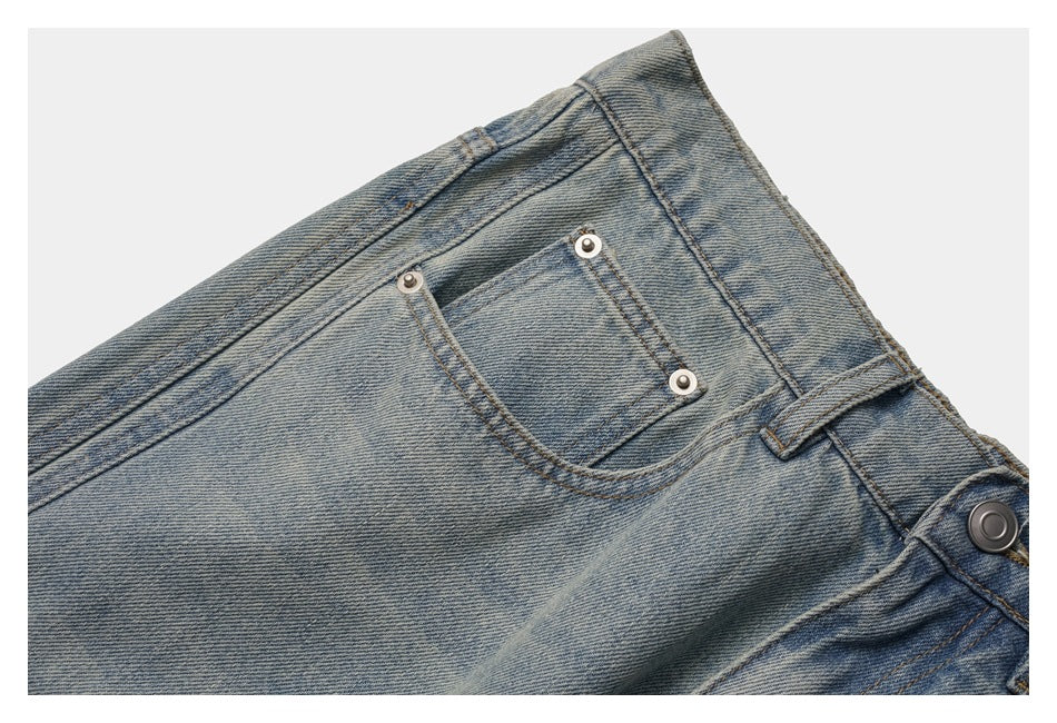 Close-up of the jeans' front coin pocket, rivets, waistband, and belt loop in faded blue denim.