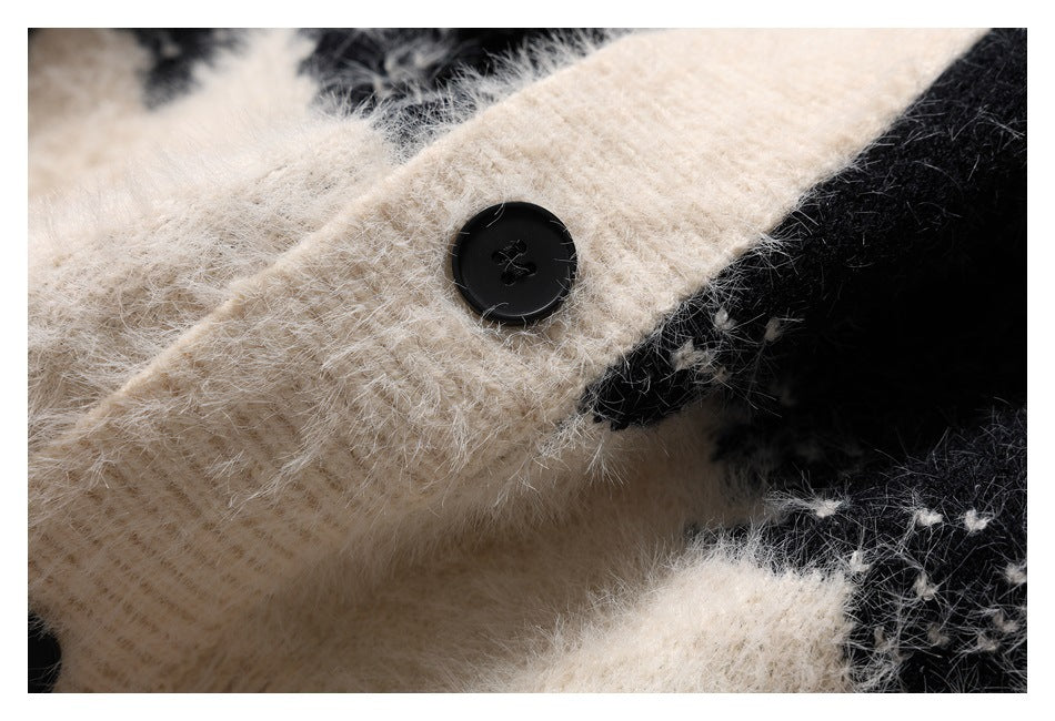 Close-up of a black button on the ivory fuzzy knit button placket, beside the sweater's black-and-ivory pattern.