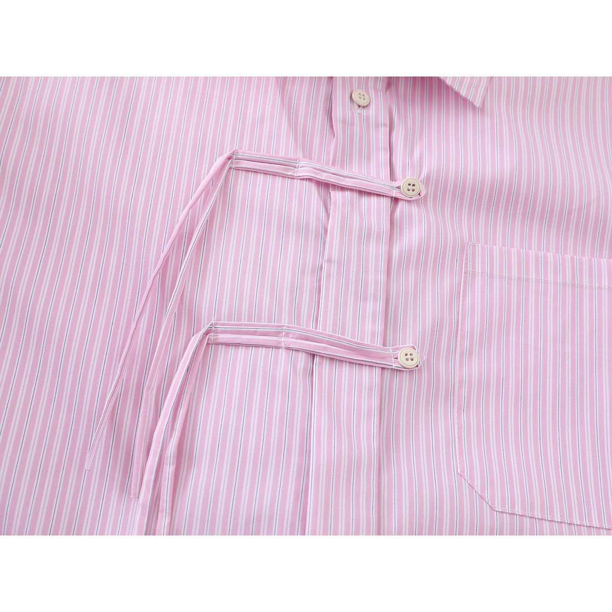 Close-up of a pink striped shirt showing two buttoned front tabs and a chest pocket.