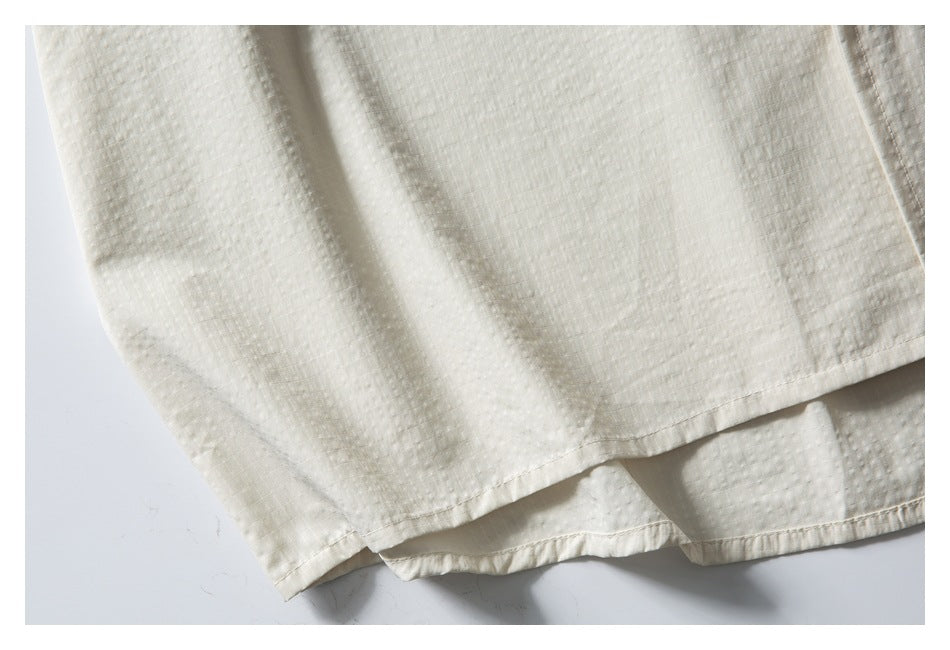 Close-up of the ivory shirt's textured fabric and layered curved hem.
