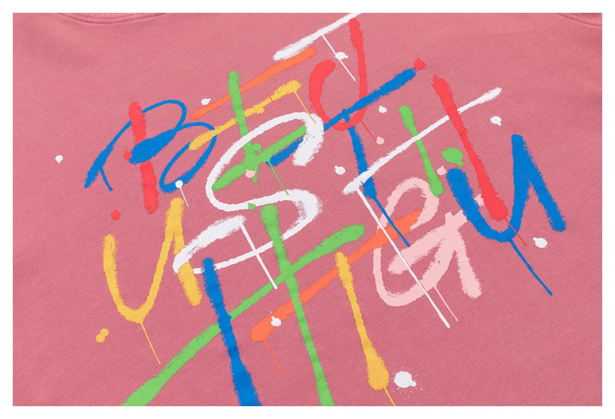 Close-up of a dusty rose sweatshirt with a bold abstract brushstroke print in bright colors.