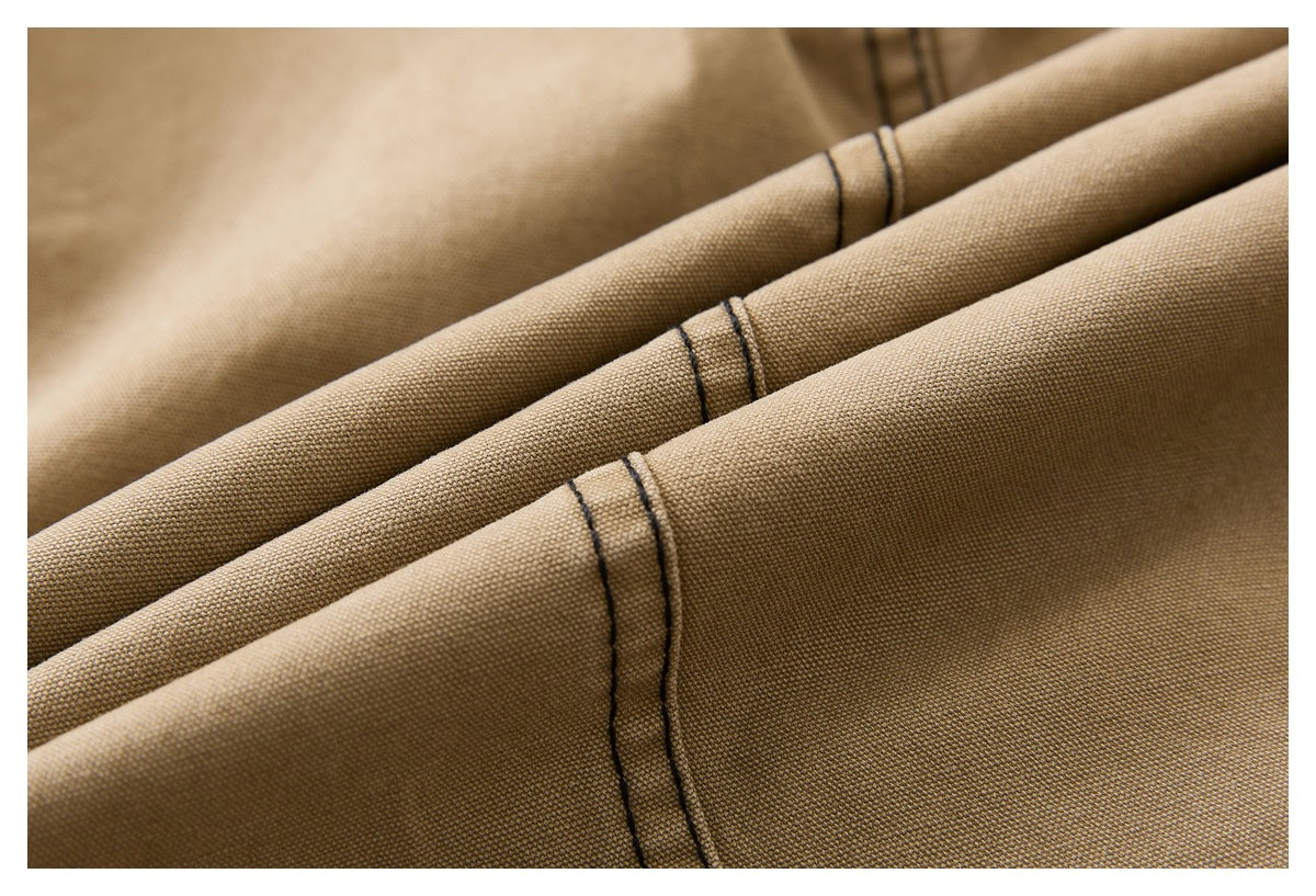 Macro view of tan pants fabric folds and dark double-stitched seams.
