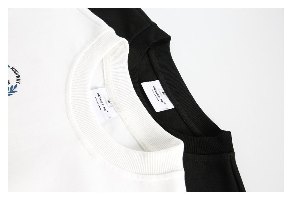 Close-up of white and black sweatshirt crew necks with ribbed collars and sewn-in labels.