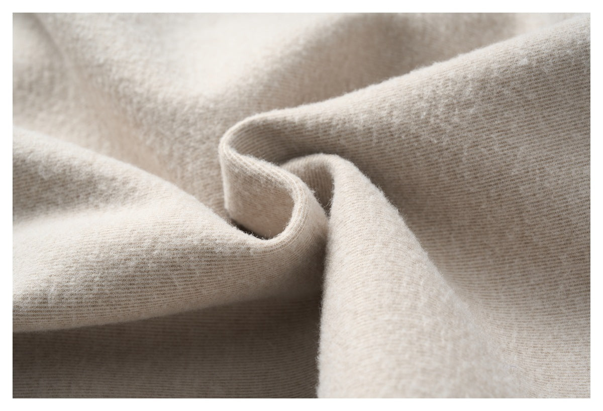 Close-up of light beige fabric arranged in soft folds, showing its fine texture.