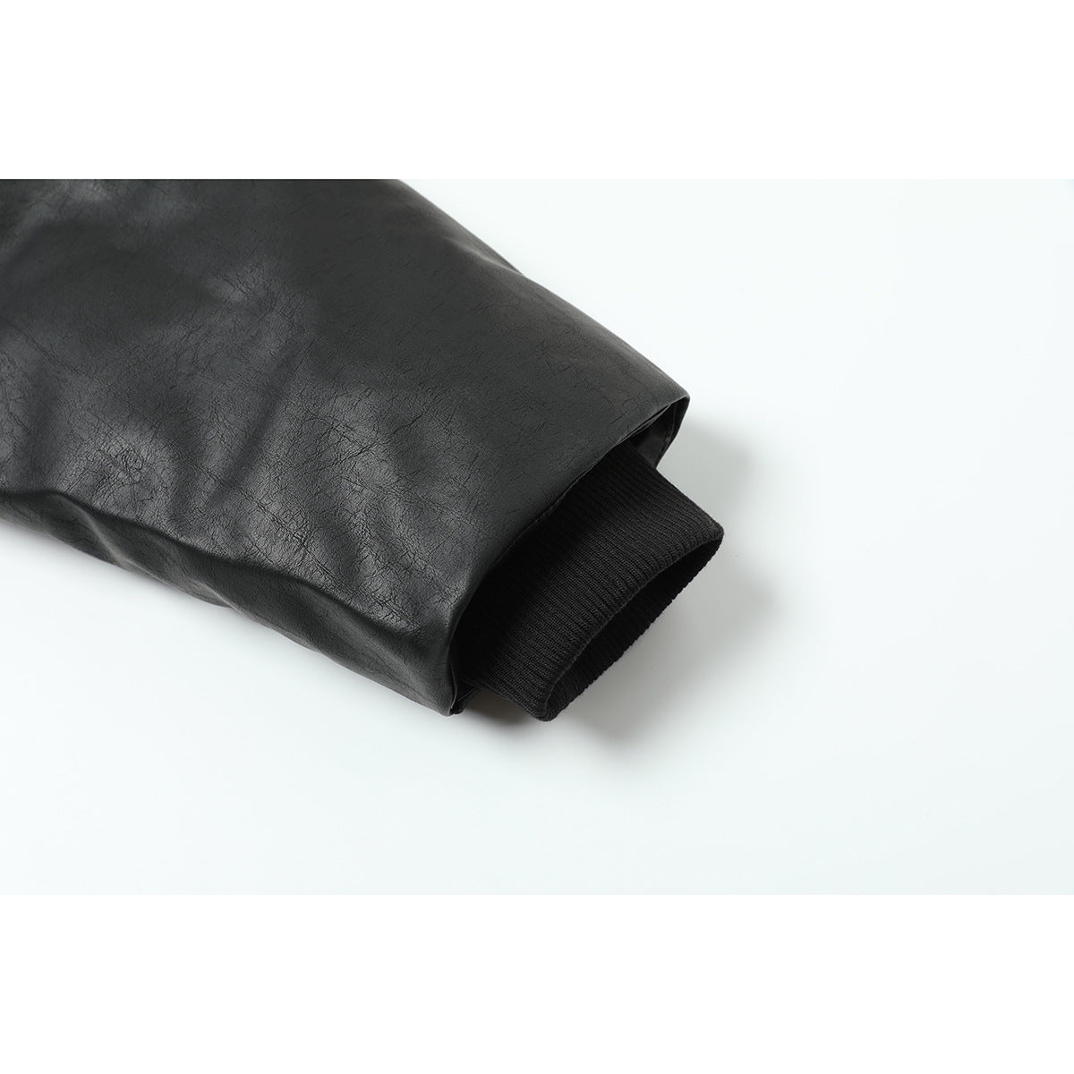 Close-up of a black jacket sleeve ending in a rib-knit cuff.