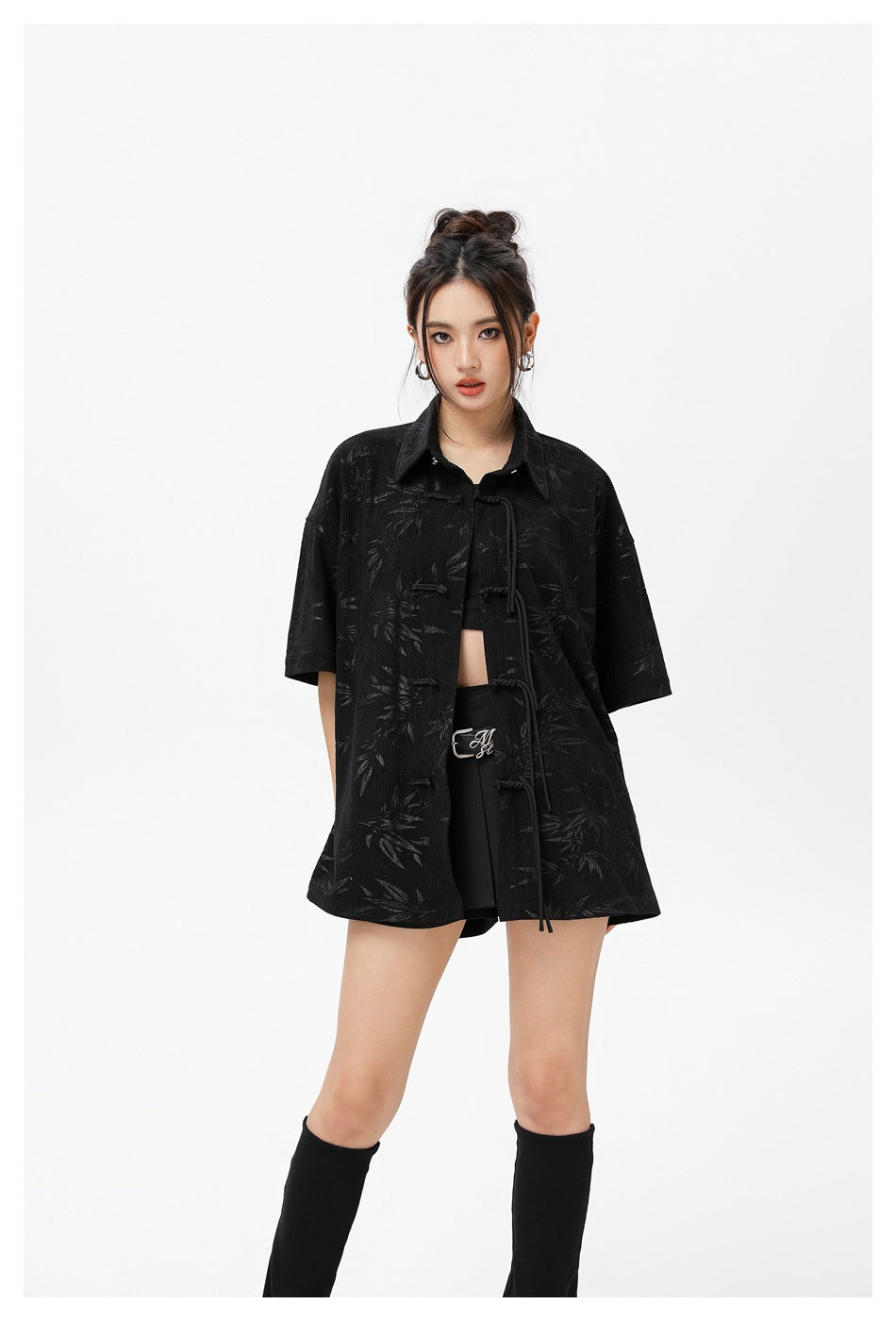 Woman in an oversized black short-sleeve shirt with tonal bamboo print and cord frog closures, front view