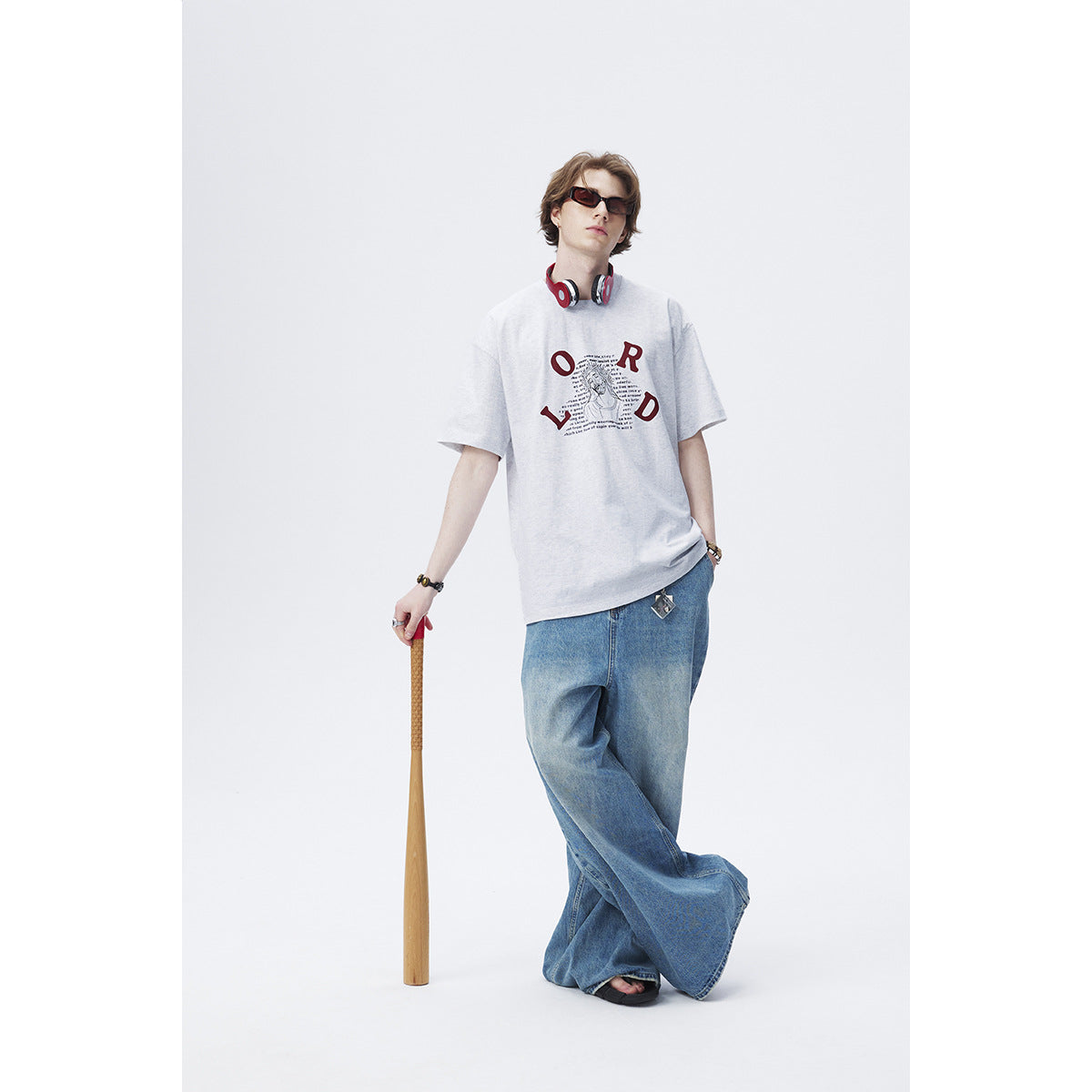 Model wearing a light gray oversized T-shirt with burgundy graphic print and wide-leg blue jeans.