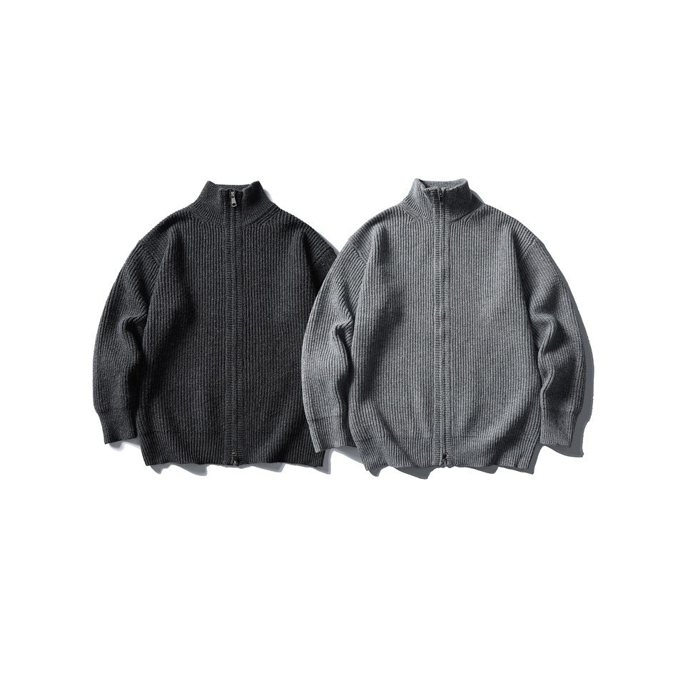 Two front-facing rib-knit zip sweaters laid flat, one charcoal and one medium gray, with high collars.