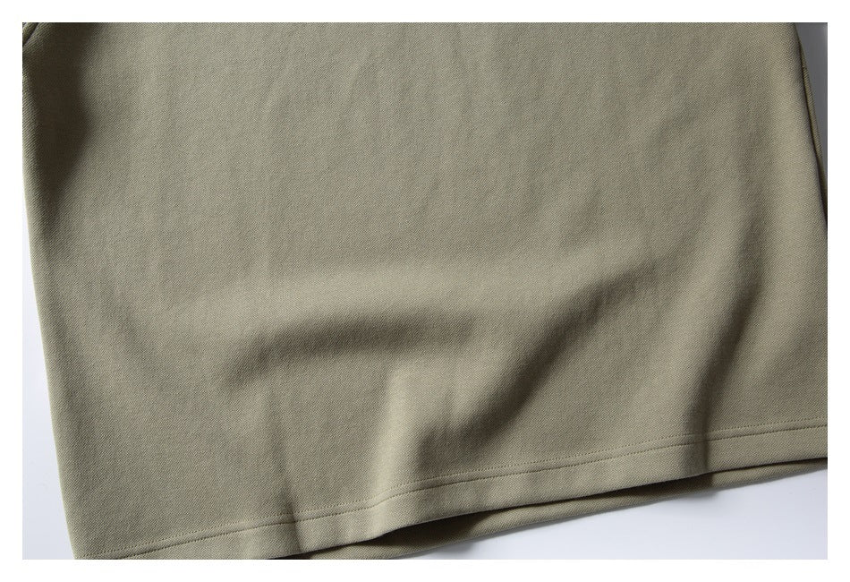 Close-up of olive-khaki garment fabric with a stitched hem.