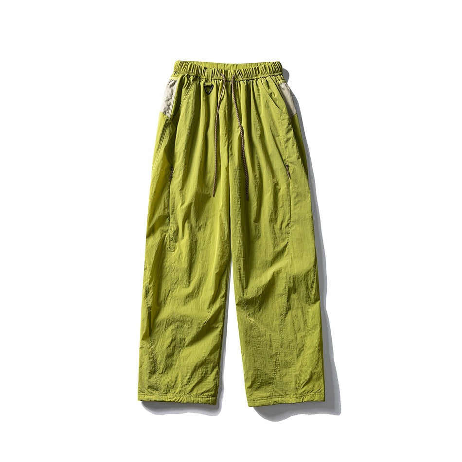 Front view of lime-green wide-leg pants with an elastic drawstring waist, side pockets and light contrasting panels.