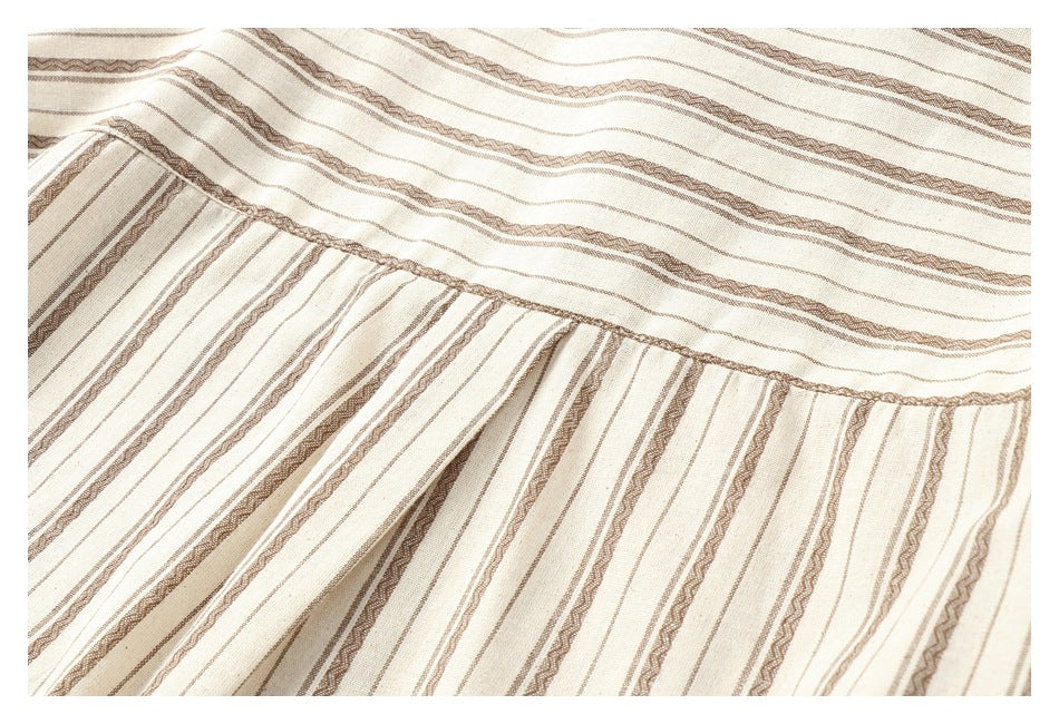 Close-up of a gathered seam joining two panels of cream fabric with brown stripes.