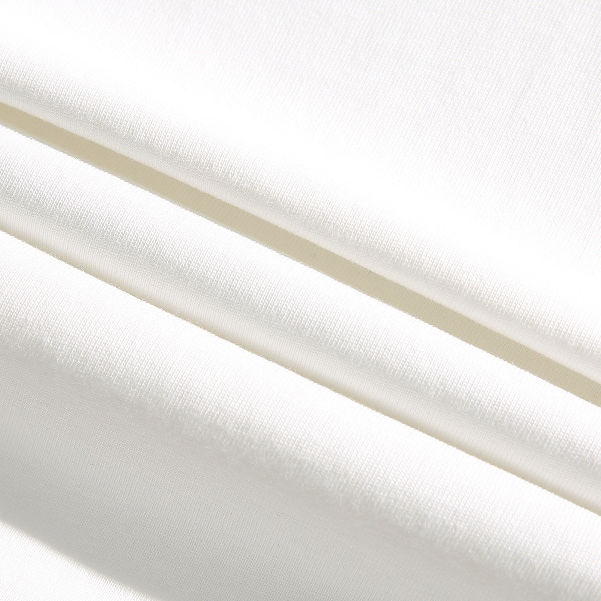 Close-up of white fabric draped in folds, showing its knit texture.