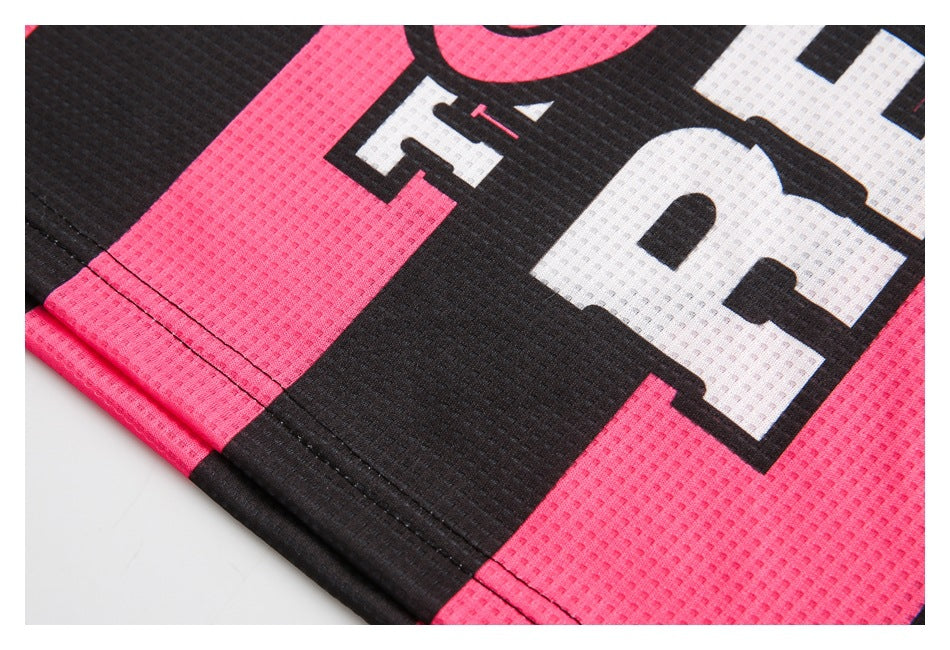 Close-up of black and bright pink perforated jersey fabric with oversized white lettering and stitched seams.