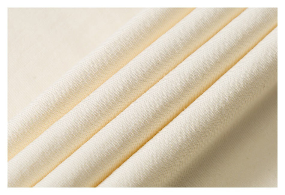 Close-up of cream garment fabric arranged in soft folds, showing its knit texture.